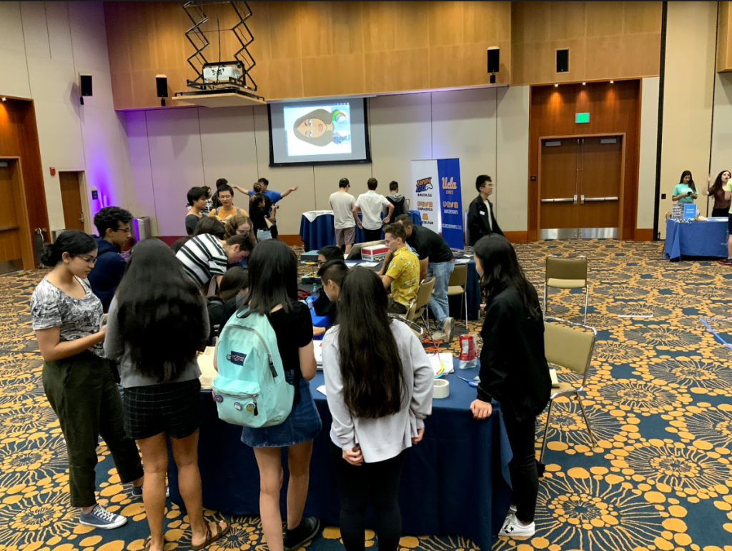 A group of students huddled around the UCLA Makerspace Booth